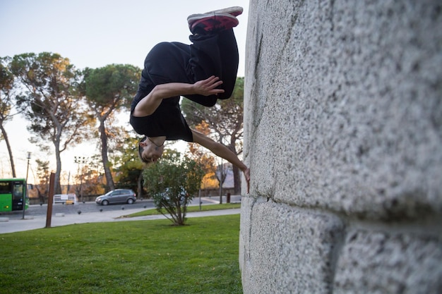 Jovem fazendo um salto de parkour em uma parede