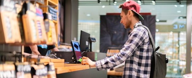 Jovem fazendo uma compra e pagando no caixa da loja