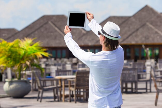 Jovem fazer uma foto no computador tablet na praia tropical