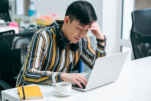 Jovem fechando os olhos enquanto se sente cansado na frente da tela de um laptop