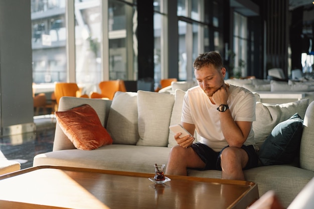 Jovem feliz a usar telemóvel no átrio do hotel