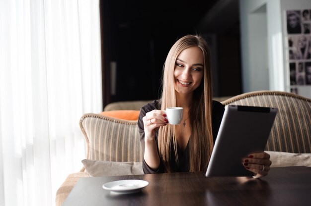 Jovem feliz bebendo chá de café e usando tablet