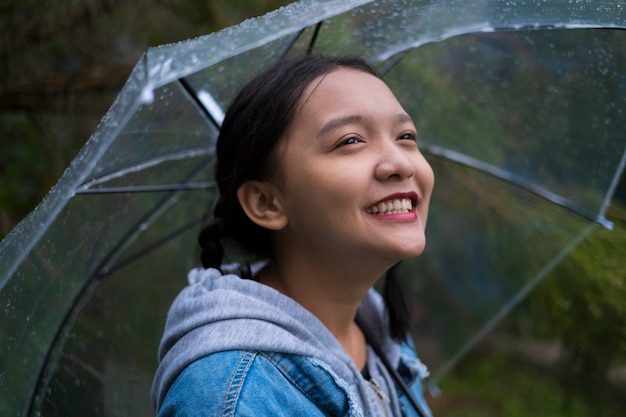 Jovem feliz brincando com chuva no jardim verde.