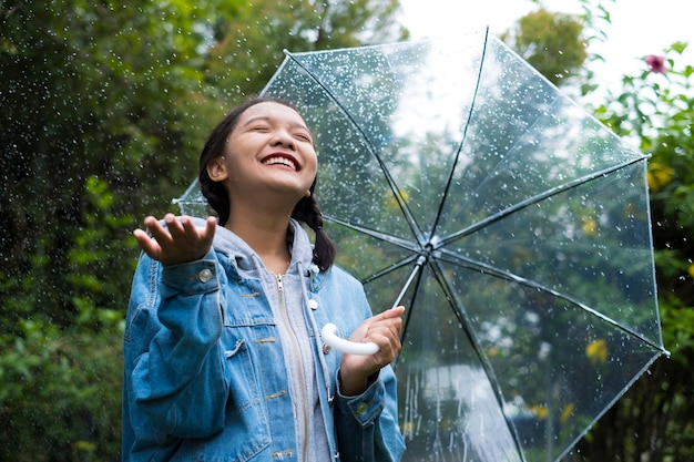 Jovem feliz brincando com chuva no jardim verde.