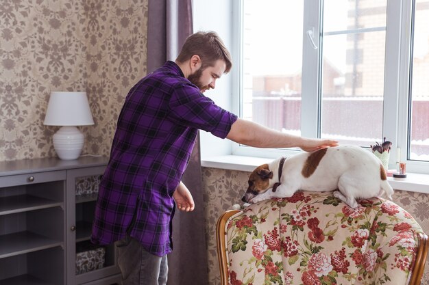 Jovem feliz brincando com seu cachorro em casa