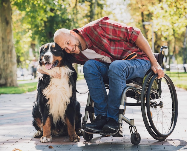 Jovem feliz com deficiência física que usa cadeira de rodas com seu cachorro