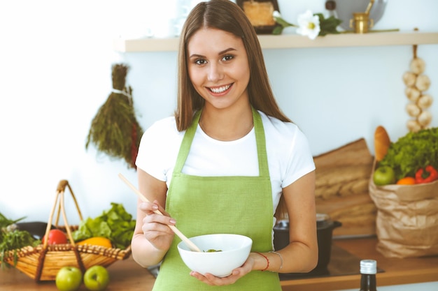 Jovem feliz cozinhando na cozinha estilo de vida de refeição saudável e conceitos culinários bom dia começa com salada fresca