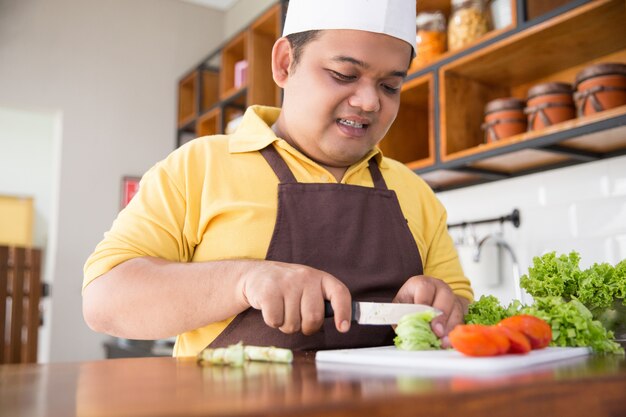 Jovem feliz cozinhando sua refeição