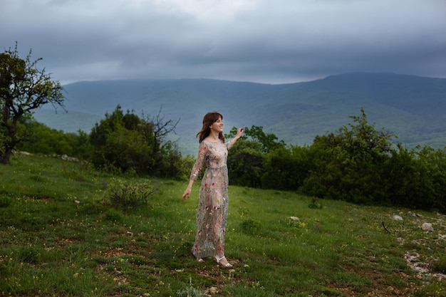 Jovem feliz de vestido longo na montanha Garota na natureza no fundo do céu azul Foto de moda