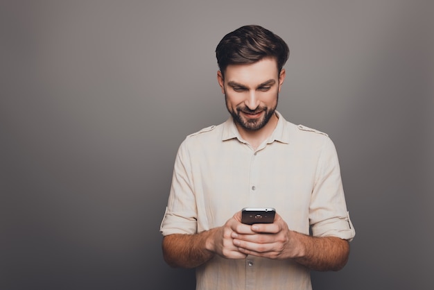 Jovem feliz digitando sms em cinza