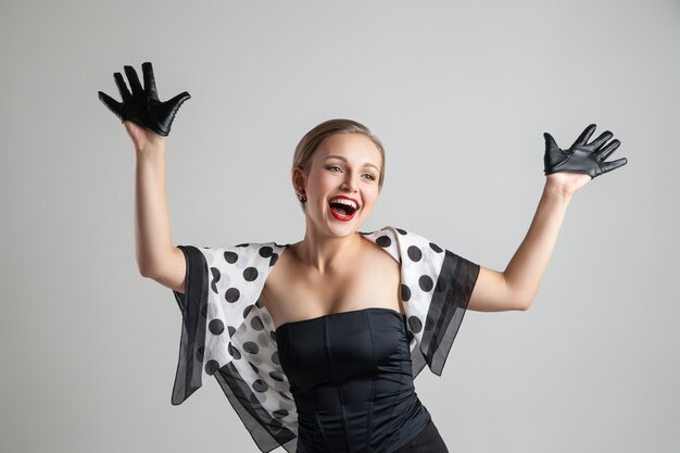 Jovem feliz e elegante mulher caucasiana posando em um fundo cinza, estilo retrô
