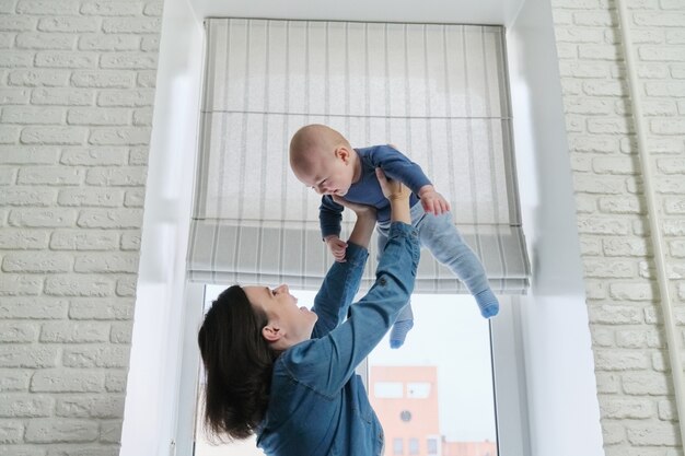 Jovem feliz e linda mãe brincando com o filho pequeno