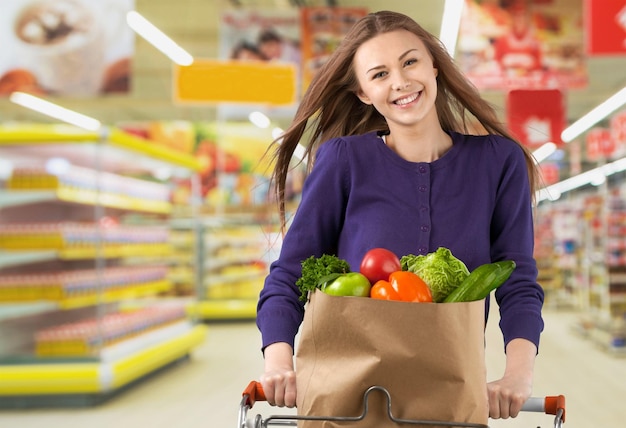 Jovem feliz empurrando o carrinho de compras na loja