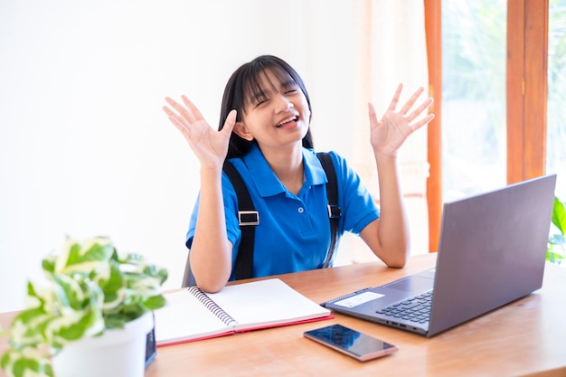 Jovem feliz estuda em casa com laptop, escola em casa.