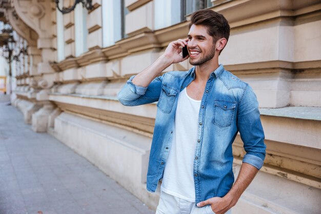 Jovem feliz falando no celular na rua