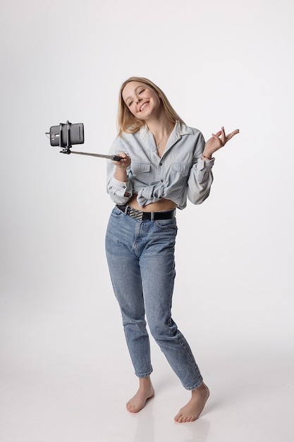 Jovem feliz fazendo auto-retrato com o smartphone anexado à vara de selfie