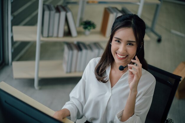 Jovem feliz feminino call center está sorrindo e olhando para a câmera.