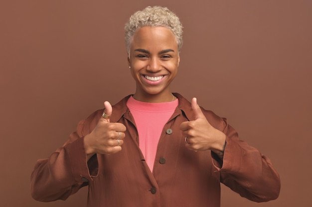 Jovem feliz mulher afro-americana milenar mostrando polegares para cima fica no estúdio