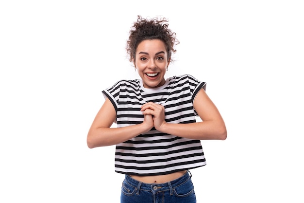 Foto jovem feliz mulher morena rizada com cabelo preto vestida com uma camiseta listrada se alegra em um branco