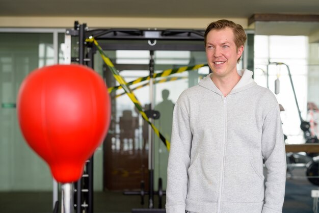 Jovem feliz pensando e pronto para o boxe na academia