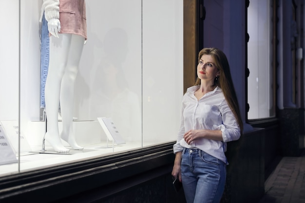Jovem feliz perto da vitrine olhando roupas para fazer compras