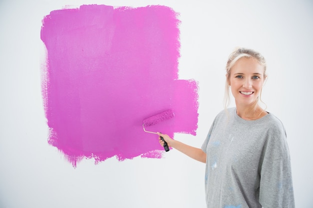 Jovem feliz pintando sua parede rosa