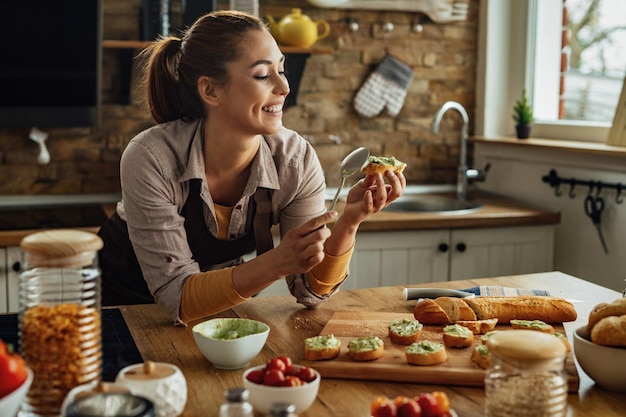 Jovem feliz preparando comida saudável e fazendo abacate na cozinha