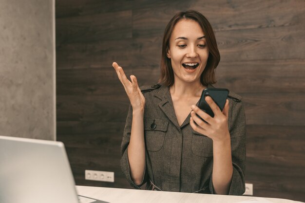 Jovem feliz que olha para o telefone e se alegra