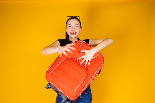 Jovem feliz sai em viagem de férias, com uma grande mala vermelha