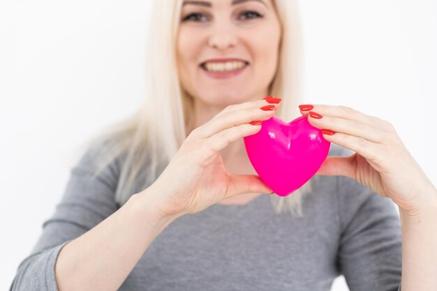 Jovem feliz segura coração de símbolo de amor vermelho. Isolado no modelo feminino de fundo de estúdio.