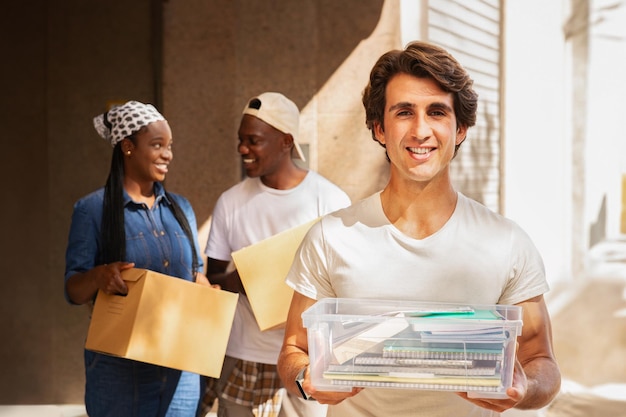 Jovem feliz segurando caixa com blocos de notas ao ar livre