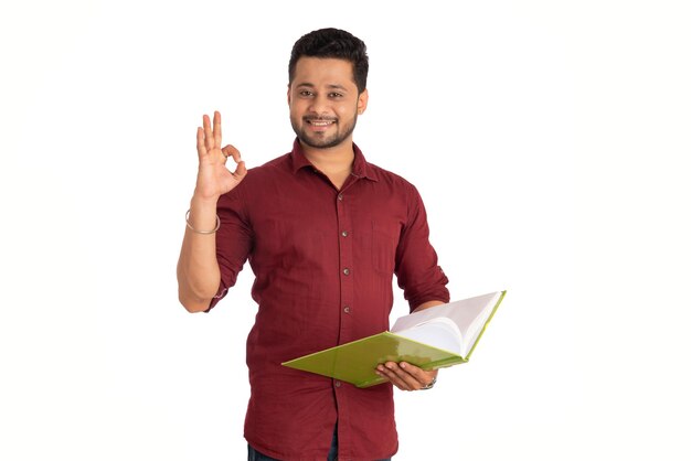 Foto jovem feliz segurando e posando com o livro em fundo branco