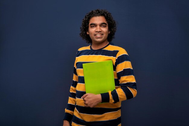 Jovem feliz segurando e posando com o livro em fundo cinza