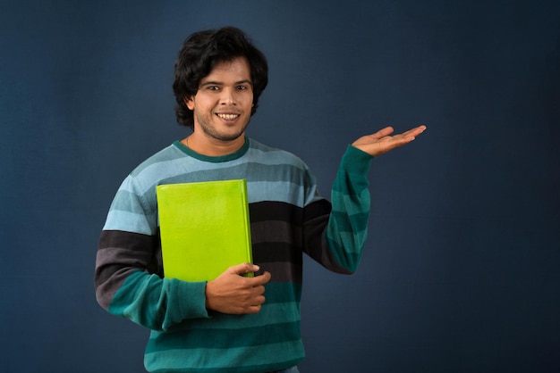 Jovem feliz segurando e posando com o livro no fundo