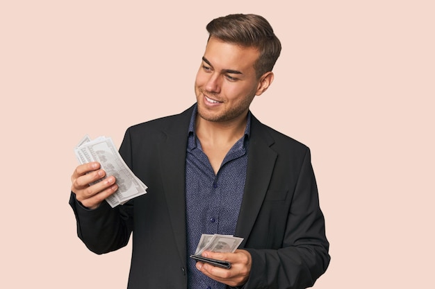 Jovem feliz segurando notas de dinheiro em um estúdio de fundo