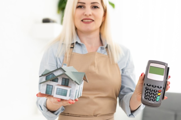 Foto jovem feliz segurando um layout de casa e terminal pos.