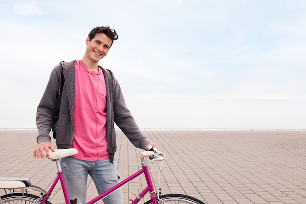 Jovem feliz sorrindo e segurando uma bicicleta retrô