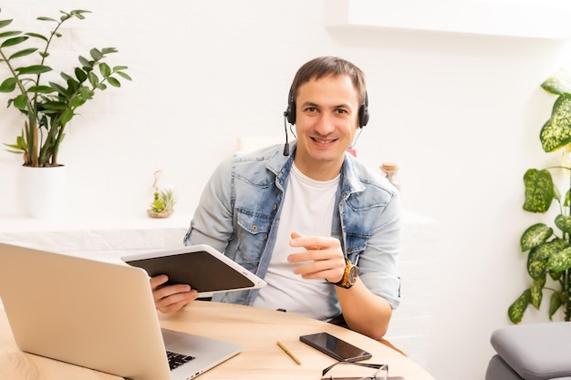 Jovem feliz sorrindo, enquanto trabalha em seu laptop para fazer todos os seus negócios no início da manhã