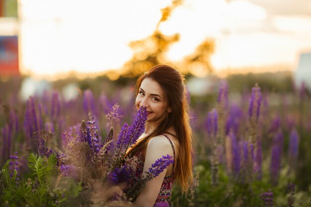 Jovem feliz sorrindo, segurando as mãos em lavanda. Foco suave, close-up