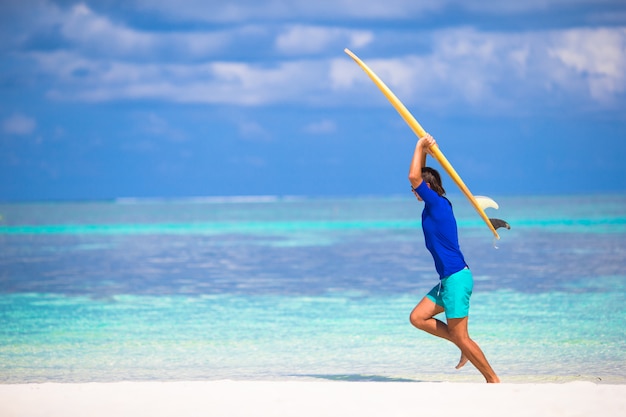 Jovem feliz surfando na costa tropical