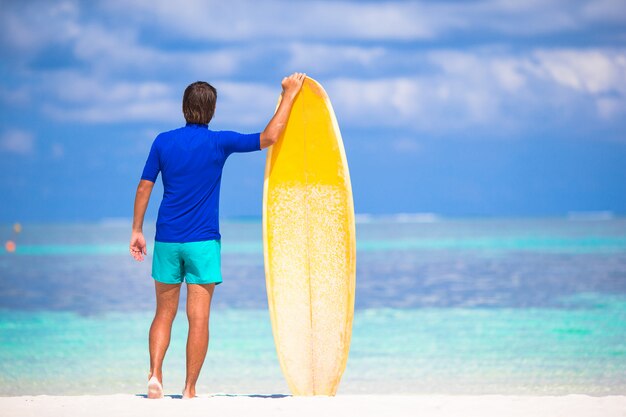 Jovem feliz surfando na costa tropical