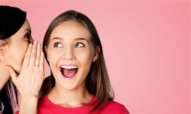 Jovem feliz sussurrando um segredo para sua amiga