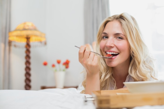 Jovem feliz tendo comida na cama