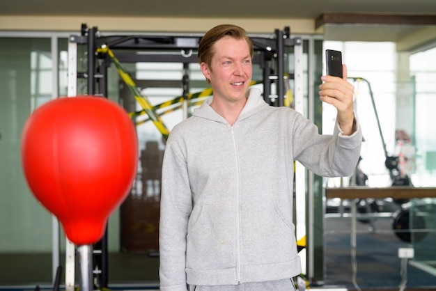 Jovem feliz tirando uma selfie e pronto para lutar boxe na academia