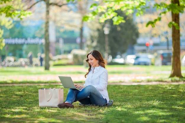 Jovem feliz trabalhando em um laptop na natureza