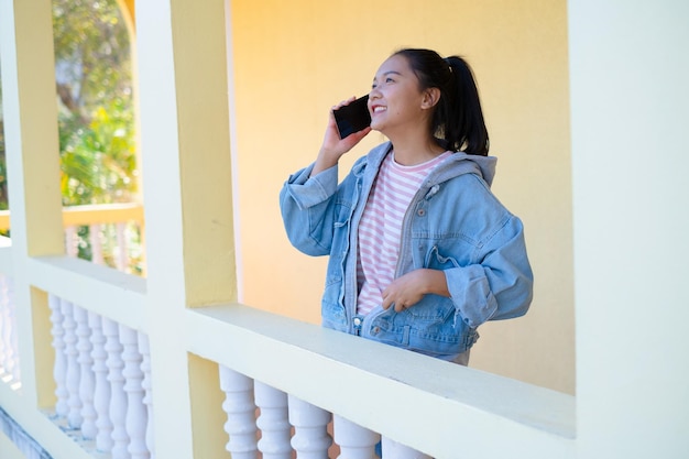 Jovem feliz usando smartphone e em pé na escola