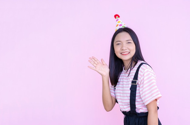 Jovem feliz usar chapéu de festa em fundo rosa, garota asiática.