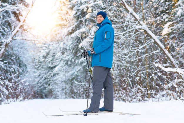 Jovem feliz vai esquiar na floresta. o homem leva um estilo de vida saudável, pratica esportes de inverno.