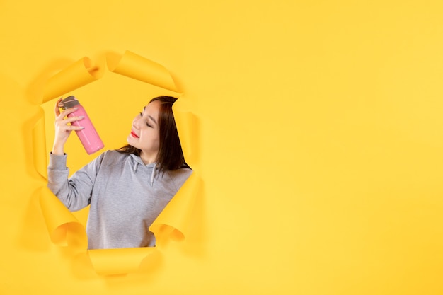 jovem fêmea com uma garrafa de água no fundo de papel amarelo rasgado atleta de ginástica fit indoor