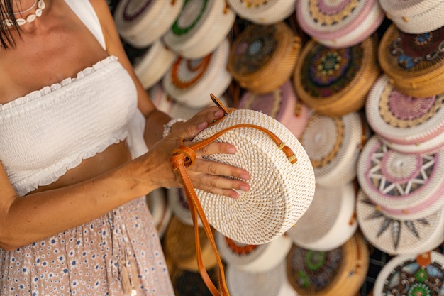 Jovem fêmea está viajando e comprando lembranças artesanais em uma loja de cestaria local. Conceito de mercado local